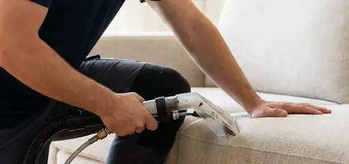 Professional upholstery cleaner deep-cleaning a fabric sofa with a handheld extraction tool, Cincinnati, OH.